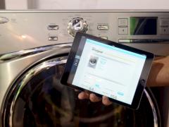 Eine Waschmaschine wird im System des Internets der Dinge mit einem Tablet gesteuert