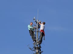 Netztechniker bringen neue Sendeanlagen auf einem Mobilfunkmast an