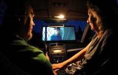 Ein Paar sitzt im Auto und schaut einen Film ber das Autoradio.