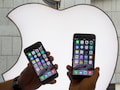 Ein Mann hlt am 19.09.2014 im Apple-Store in Mnchen (Bayern) zwei Iphone 6 Modelle vor das Apple-Logo.