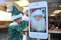 Ein Weihnachtself steht im Schaufenster eines Elektronikladens in Mnchen neben einem Smartphone, auf dessen Display ein Nikolaus zu sehen ist.