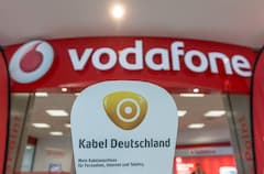Das Logo des Kabelnetzbetreibers Kabel Deutschland vor dem Schriftzug des Mobilfunkanbieters Vodafone an einem Vodafone-Geschft.