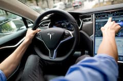 Ein Mann sitzt in Mnchen (Bayern) in einem Tesla Model S auf dem Fahrersitz vor einem Showroom des Autoherstellers.