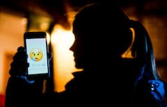 in junges Mdchen zeigt das Display eines Smartphones mit einem weinenden Emoji beim Messenger WhatsApp (gestellte Szene).