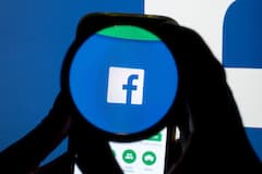 Das Icon der Social Media-Plattform Facebook ist auf einem Handy durch eine Linse zu sehen.