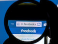 Der Schriftzug der Social Media-Plattform Facebook ist auf einem Handy durch eine Linse zu sehen.