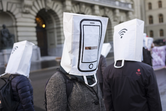 Proteste in Bern mit Papiertten auf dem Kopf, auf denen Mobiltelefone abgebildet sind, um whrend der Nationalratssitzung vor dem Ausbau des Mobilfunknetzes auf den 5G Standard zu warnen 