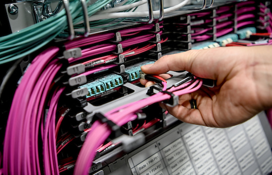 Ein IT-Spezialist der Bahn zieht am ehemaligen Server den Stecker: Eine Glasfaserverbindung wird getrennt.