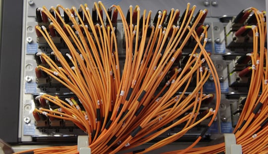 sehr viele orange Kabel entspringen einem Steckfeld und werden am unteren Rand des Bilds gebndelt